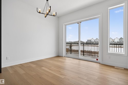 Room featuring light hardwood floors, a modern chandelier, and access to an outdoor balcony - 27 Rosewood Way, St. Albert, AB - Indoor Photo Showing Other Room