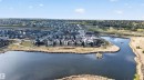 Aerial perspective showcasing a residential community bordering a natural pond with an island feature - 27 Rosewood Way, St. Albert, AB  - Outdoor With Body Of Water With View 