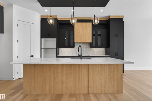 The kitchen features a spacious island with a light-toned wood finish and a white countertop - 27 Rosewood Way, St. Albert, AB - Indoor Photo Showing Kitchen