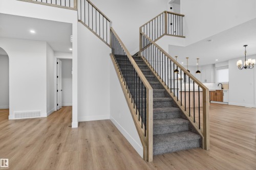Staircase featuring wood-finish railings and black balusters, carpeted treads, and light wood-finish flooring - 27 Redpoll Wynd, St. Albert, AB - Indoor Photo Showing Other Room
