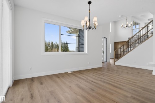 Expansive open-concept living space featuring wood-finish flooring, a large window with white trim, and a black wrought iron chandelier - 27 Redpoll Wynd, St. Albert, AB - Indoor Photo Showing Other Room