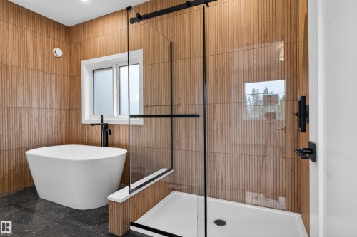 Freestanding soaking tub with black hardware, complementing a glass-enclosed shower featuring a white shower pan and black framing - 27 Redpoll Wynd, St. Albert, AB - Indoor Photo Showing Bathroom