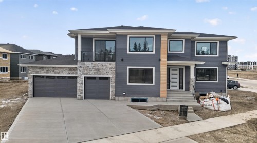 Modern two-story residence featuring gray siding, stone accents, and a light wood-finish vertical panel - 27 Redpoll Wynd, St. Albert, AB - Outdoor With Facade