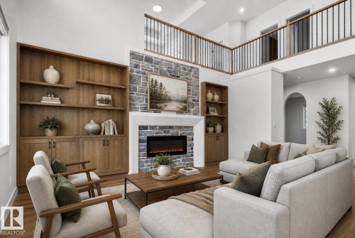 Two-story living area featuring a stone fireplace with an electric insert, built-in wood cabinetry, wood-finish flooring, an arched entryway, and an upper-level railing with black spindles - 27 Redpoll Wynd, St. Albert, AB - Indoor Photo Showing Living Room With Fireplace