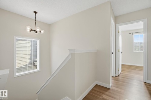 Hall with an upstairs landing, light wood-style flooring, a chandelier, and a textured ceiling - 3014 31 Avenue, Edmonton, AB - Indoor Photo Showing Other Room