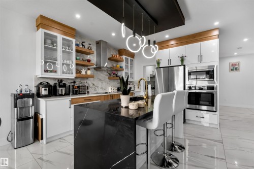 Kitchen with glass insert cabinets, light marble finish floors, appliances with stainless steel finishes, a kitchen island with sink, and recessed lighting - 15518 13A Avenue, Edmonton, AB - Indoor Photo Showing Kitchen With Upgraded Kitchen