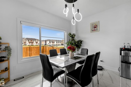 Dining space with a residential view and light marble finish floors - 15518 13A Avenue, Edmonton, AB - Indoor Photo Showing Dining Room