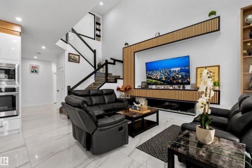 Living area featuring recessed lighting, stairs, light marble finish floors, and a premium fireplace - 15518 13A Avenue, Edmonton, AB - Indoor Photo Showing Living Room