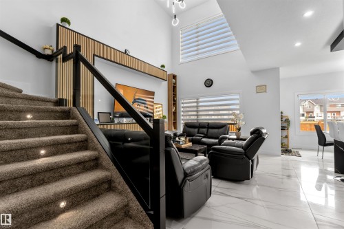 Living room featuring healthy amount of natural light, recessed lighting, a towering ceiling, light marble finish floors, and stairway - 15518 13A Avenue, Edmonton, AB - Indoor Photo Showing Other Room