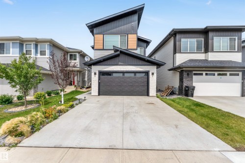 Contemporary home with stone siding, a garage, concrete driveway, and board and batten siding - 15518 13A Avenue, Edmonton, AB - Outdoor With Facade