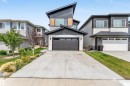 Contemporary home with stone siding, a garage, concrete driveway, and board and batten siding - 15518 13A Avenue, Edmonton, AB  - Outdoor With Facade 