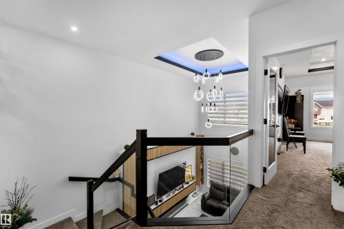 Stairway with carpet floors, a chandelier, a tray ceiling, and recessed lighting - 15518 13A Avenue, Edmonton, AB - Indoor Photo Showing Other Room