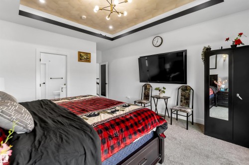Bedroom with light carpet, a raised ceiling, a chandelier, and ensuite bathroom - 15518 13A Avenue, Edmonton, AB - Indoor Photo Showing Bedroom