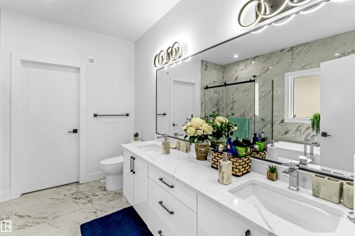 Bathroom featuring light marble finish flooring, a marble finish shower, double vanity, and a freestanding bath - 15518 13A Avenue, Edmonton, AB - Indoor Photo Showing Bathroom