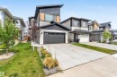 View of front of property with stone siding, a garage, board and batten siding, driveway, and a front lawn - 15518 13A Avenue, Edmonton, AB  - Outdoor With Facade 