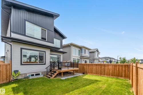 Rear view of property with a deck, board and batten siding, a fenced backyard, and a residential view - 15518 13A Avenue, Edmonton, AB - Outdoor