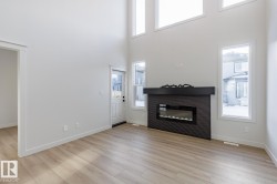 Foyer featuring light wood-type flooring, a glass covered fireplace, and a high ceiling - 