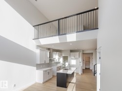 Kitchen featuring a high ceiling, white cabinetry, a kitchen island with sink, light wood-type flooring, and decorative backsplash - 