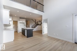 Kitchen with white cabinets, a center island with sink, light wood-type flooring, a breakfast bar area, and a high ceiling - 
