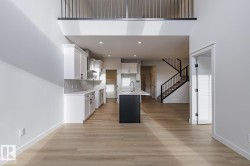Kitchen featuring white cabinets, a center island with sink, backsplash, light wood finished floors, and recessed lighting - 