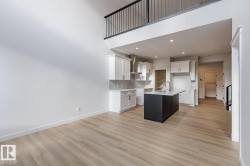 Kitchen featuring white cabinetry, an island with sink, backsplash, wall chimney exhaust hood, and light wood-style flooring - 