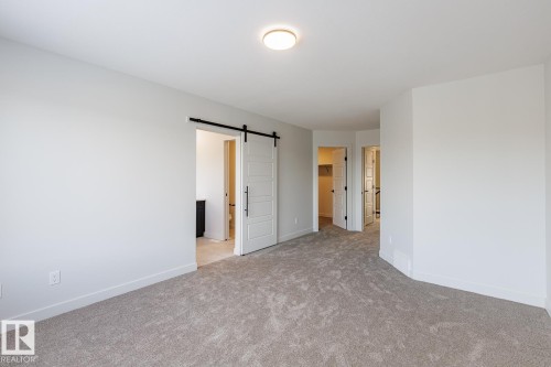 Unfurnished room featuring a barn door and light colored carpet - 3719 42 Avenue, Beaumont, AB - Indoor Photo Showing Other Room