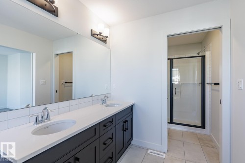 Bathroom with a stall shower, double vanity, light tile patterned floors, and backsplash - 3719 42 Avenue, Beaumont, AB - Indoor Photo Showing Bathroom