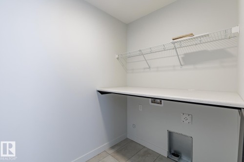 Laundry area with light tile patterned floors and hookup for a washing machine - 3719 42 Avenue, Beaumont, AB - Indoor With Storage
