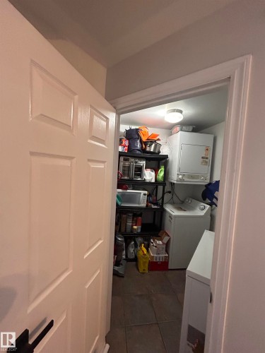 Laundry area featuring dark tile patterned flooring and stacked washer and clothes dryer - 506 10046 110 Street, Edmonton, AB - Indoor Photo Showing Other Room