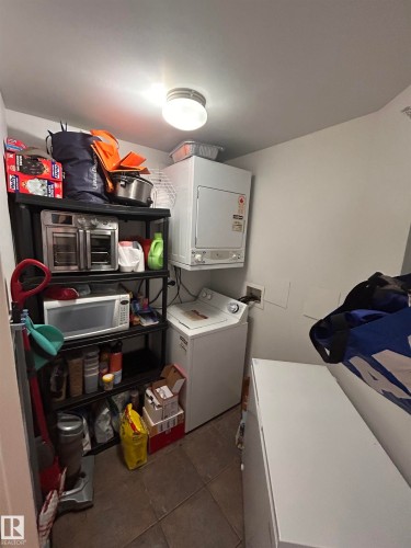 Laundry area with dark tile patterned floors and hookup for a washing machine - 506 10046 110 Street, Edmonton, AB - Indoor Photo Showing Laundry Room