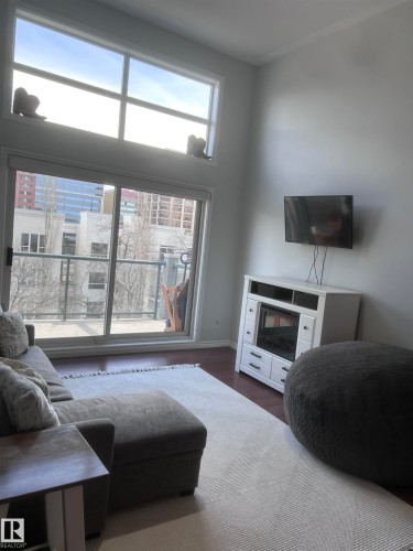 Living area featuring dark wood-type flooring and baseboards - 506 10046 110 Street, Edmonton, AB - Indoor