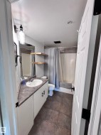 Full bathroom with vanity, dark tile patterned floors, and shower / bath combo with shower curtain - 