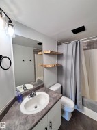 Bathroom featuring a shower with curtain, vanity, and dark tile patterned flooring - 