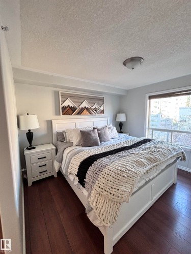 Bedroom featuring a textured ceiling and dark wood-style floors - 506 10046 110 Street, Edmonton, AB - Indoor Photo Showing Bedroom