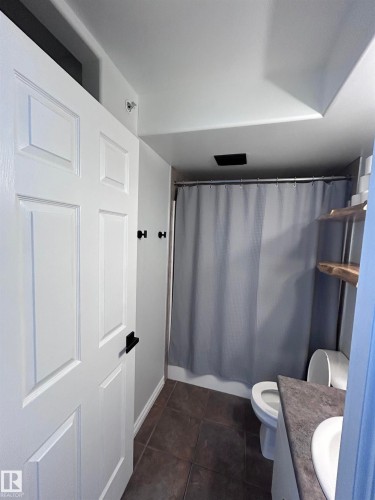Full bath featuring vanity, shower / tub combo, and dark tile patterned floors - 506 10046 110 Street, Edmonton, AB - Indoor Photo Showing Other Room