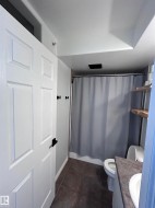 Full bath featuring vanity, shower / tub combo, and dark tile patterned floors - 