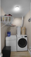 Laundry room featuring a textured ceiling, light wood finished floors, and washing machine and dryer - 