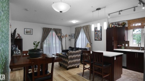 Kitchen featuring decorative backsplash, a center island, hanging light fixtures, light countertops, and rail lighting - 105 2584 Anderson Way, Edmonton, AB - Indoor