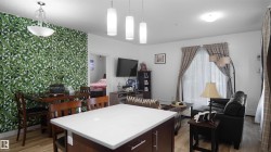 Kitchen featuring dark brown cabinetry, light countertops, a kitchen island, pendant lighting, and light wood finished floors - 