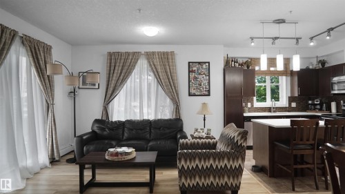 Living area with a textured ceiling and light wood-type flooring - 105 2584 Anderson Way, Edmonton, AB - Indoor