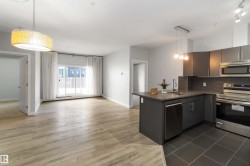 Kitchen featuring stainless steel appliances, hanging light fixtures, dark countertops, tasteful backsplash, and open floor plan - 
