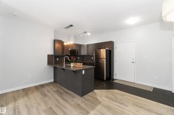 Kitchen featuring hanging light fixtures, dark wood-style flooring, decorative backsplash, stainless steel appliances, and a breakfast bar - 