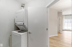 Washroom with estacked washer and dryer and light wood-style floors - 