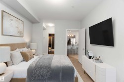 Bedroom with connected bathroom, freestanding refrigerator, and light colored carpet - 