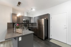 Kitchen featuring appliances with stainless steel finishes, hanging light fixtures, decorative backsplash, a peninsula, and a kitchen breakfast bar - 