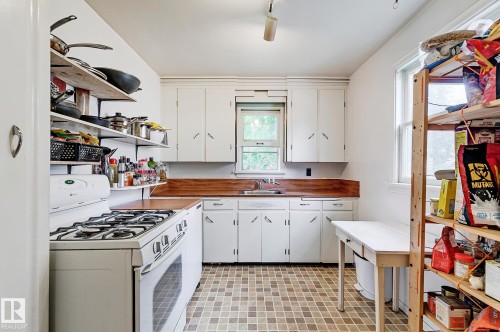 Kitchen featuring white gas range oven, white cabinetry, open shelves, and light flooring - 11559 80 Avenue, Edmonton, AB - Indoor Photo Showing Kitchen