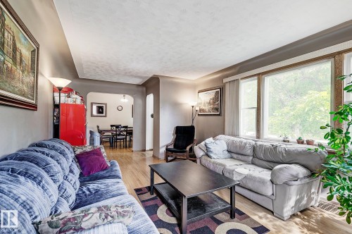 Living area featuring arched walkways, a textured ceiling, and light wood finished floors - 11559 80 Avenue, Edmonton, AB - Indoor Photo Showing Living Room