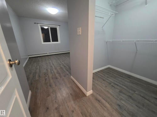Spacious closet with dark wood-style flooring and baseboard heating - 106 4903 47 Avenue, Stony Plain, AB - Indoor