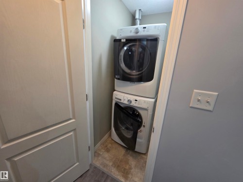 Washroom featuring estacked washer and dryer and baseboards - 106 4903 47 Avenue, Stony Plain, AB - Indoor Photo Showing Laundry Room
