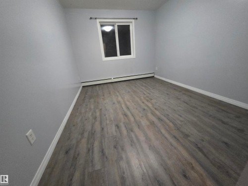 Spare room with wood finished floors and baseboard heating - 106 4903 47 Avenue, Stony Plain, AB - Indoor Photo Showing Other Room